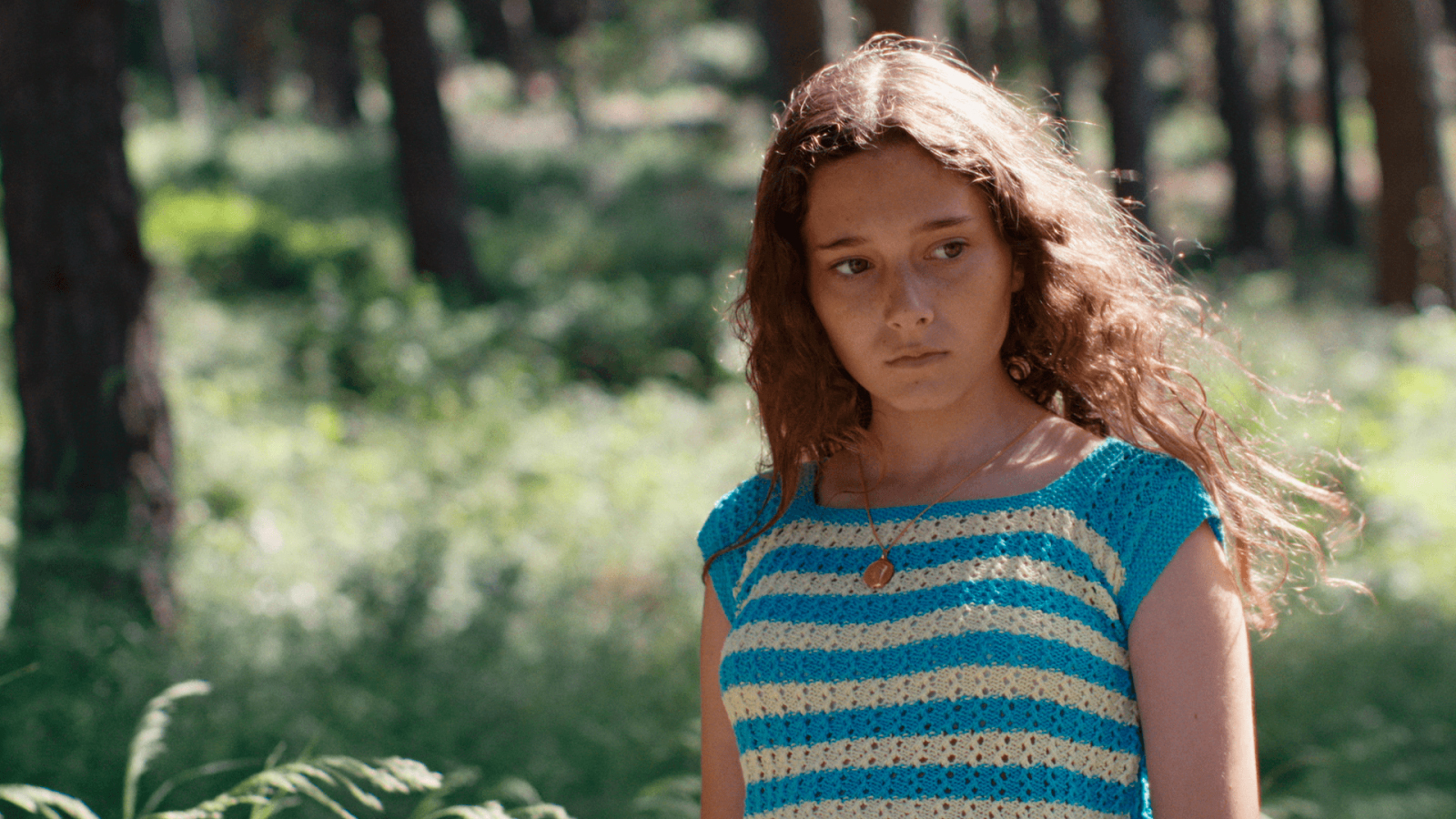 Una nena d'onze anys (Laia Artigas) està enmig d'un bosc, contemplant el seu voltant.